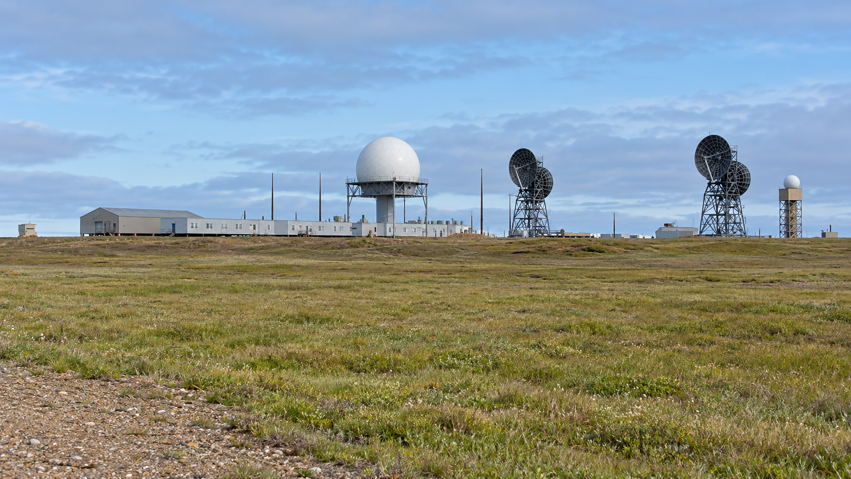 Historical reconstruction of Point Lonely with its module train, raised white radome, and two dark radar antenna assemblies on flat Arctic tundra