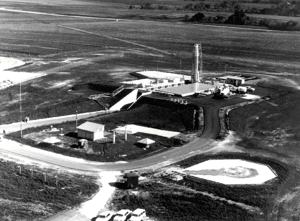 An Atlas E missile towers above its launch facility. The underground launch operations building, marked by two square metal ventilators, is in the foreground.