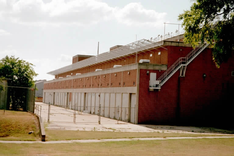 Nike Hercules Final Assembly and Test Building. A total of 12 systems could be in various states of test at one time. The ground level openings held the generator sets (vents can be seen on the roof. Nest level held the TTR and MTR radars facing a test tower near the Nike Ajax buildings (see next photo). TRR and LOPARS were on the upper roof. Assembly of the units was immediately behind the control trailers. There were large overhead tracked cranes to move the units around. The elevators at the end of the building were large enough to drive a small truck-trailer to the roofs. The building while three stories was taller than a 5 story building across the street.