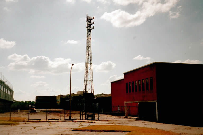 Nike Ajax Test Building to the left. The main factory building is to the right. Large machine shop cabinet assembly and plug-in assemblies were built here. Nike Hercules Test Tower is shown in the middle. There were 6 antenna positions. The RF Test Sets were in the small building at the tower base.