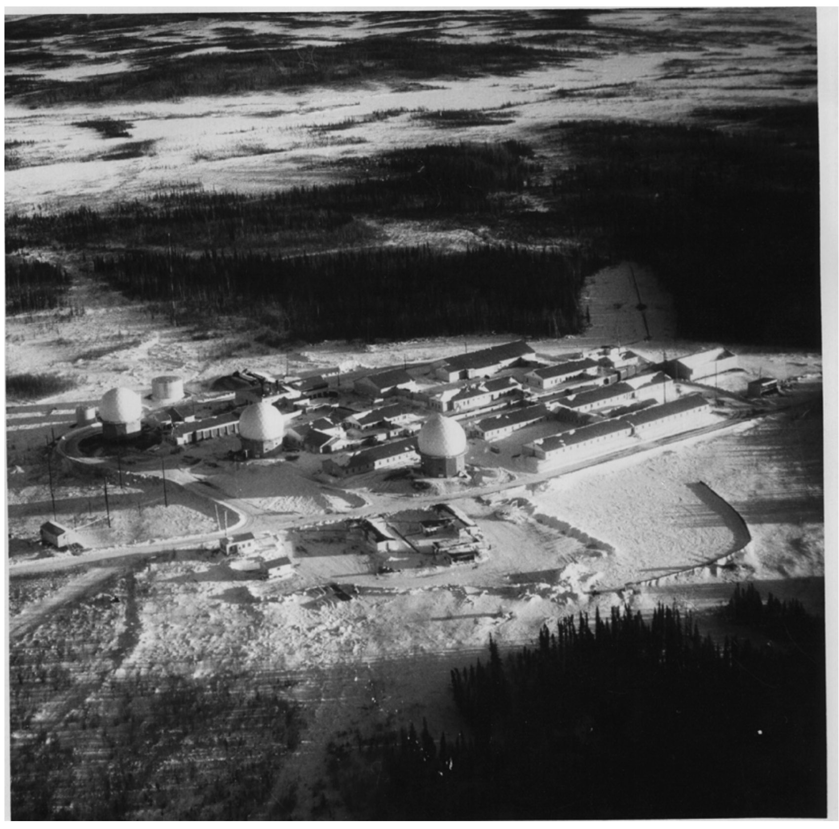 Undated aerial photograph of Campion Air Force Station showing three radomes and rows of connected buildings amid Yukon lowland forest