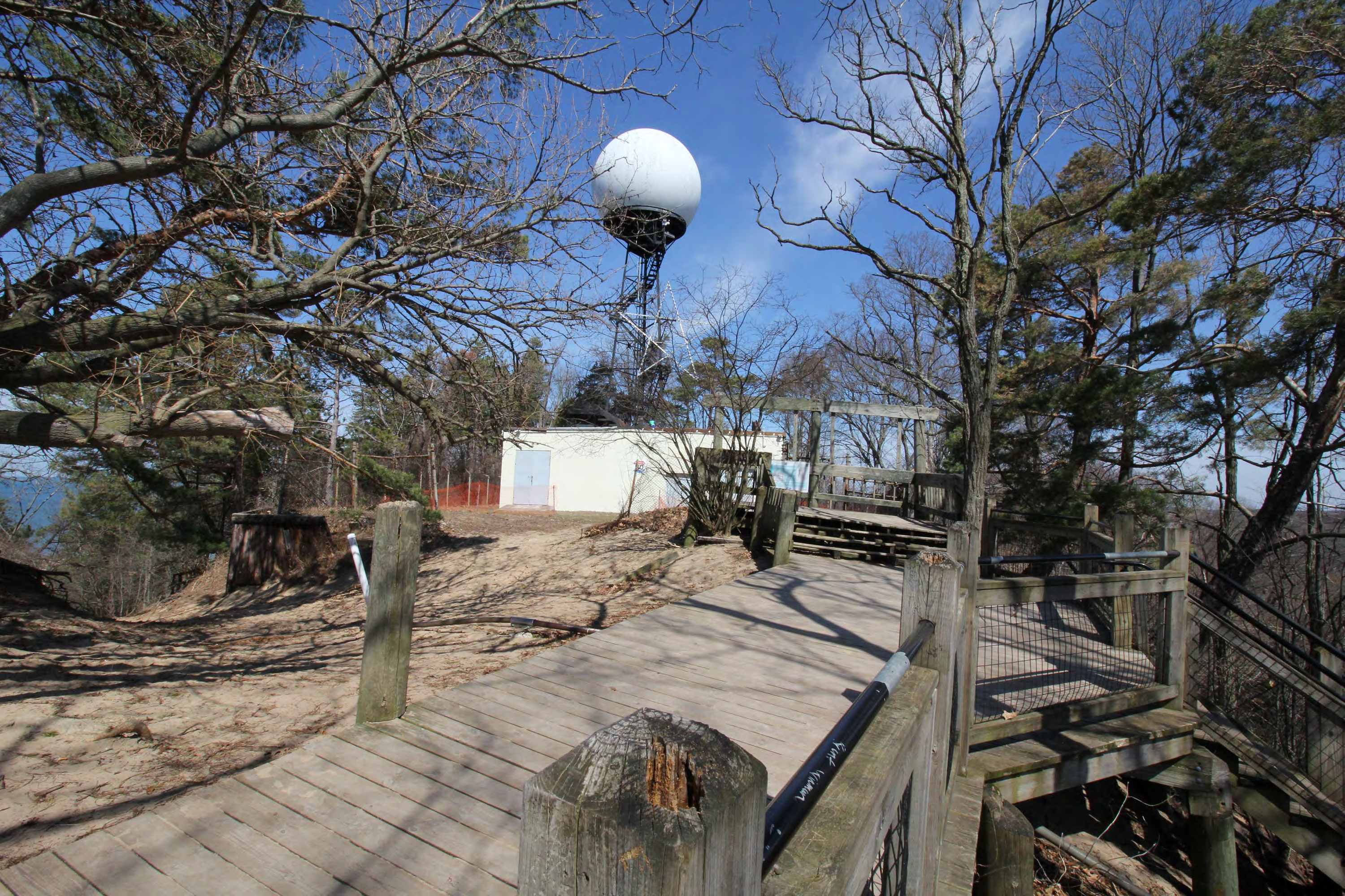Mt. Baldhead Park observation deck and stairs foreground, Mt. Baldhead Park Trail left with Lake Michigan in background, radar annex ahead, from south
