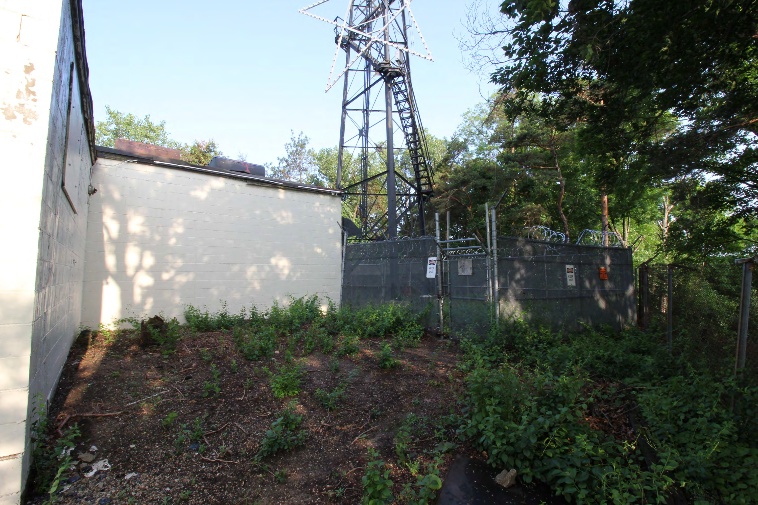 Equipment room east exterior wall, antenna tower security fence, from southeast