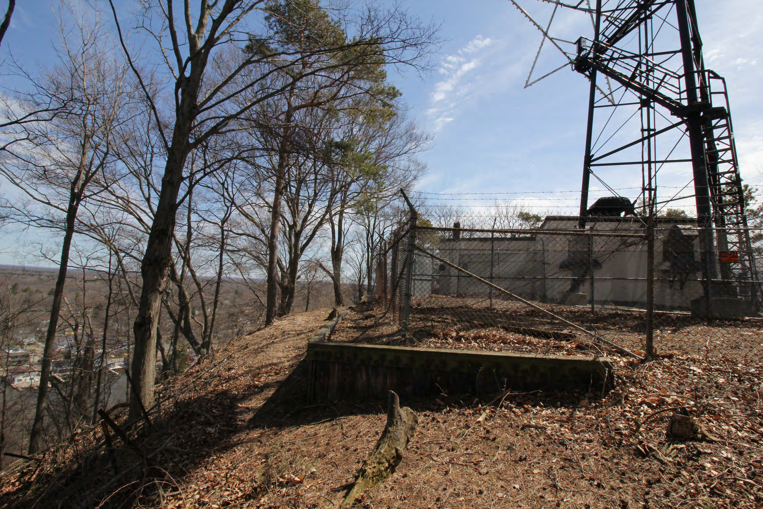 View of wooden retaining wall, annex perimeter fence, antenna tower fence, towerbase, equipment, and generator building, from north.
