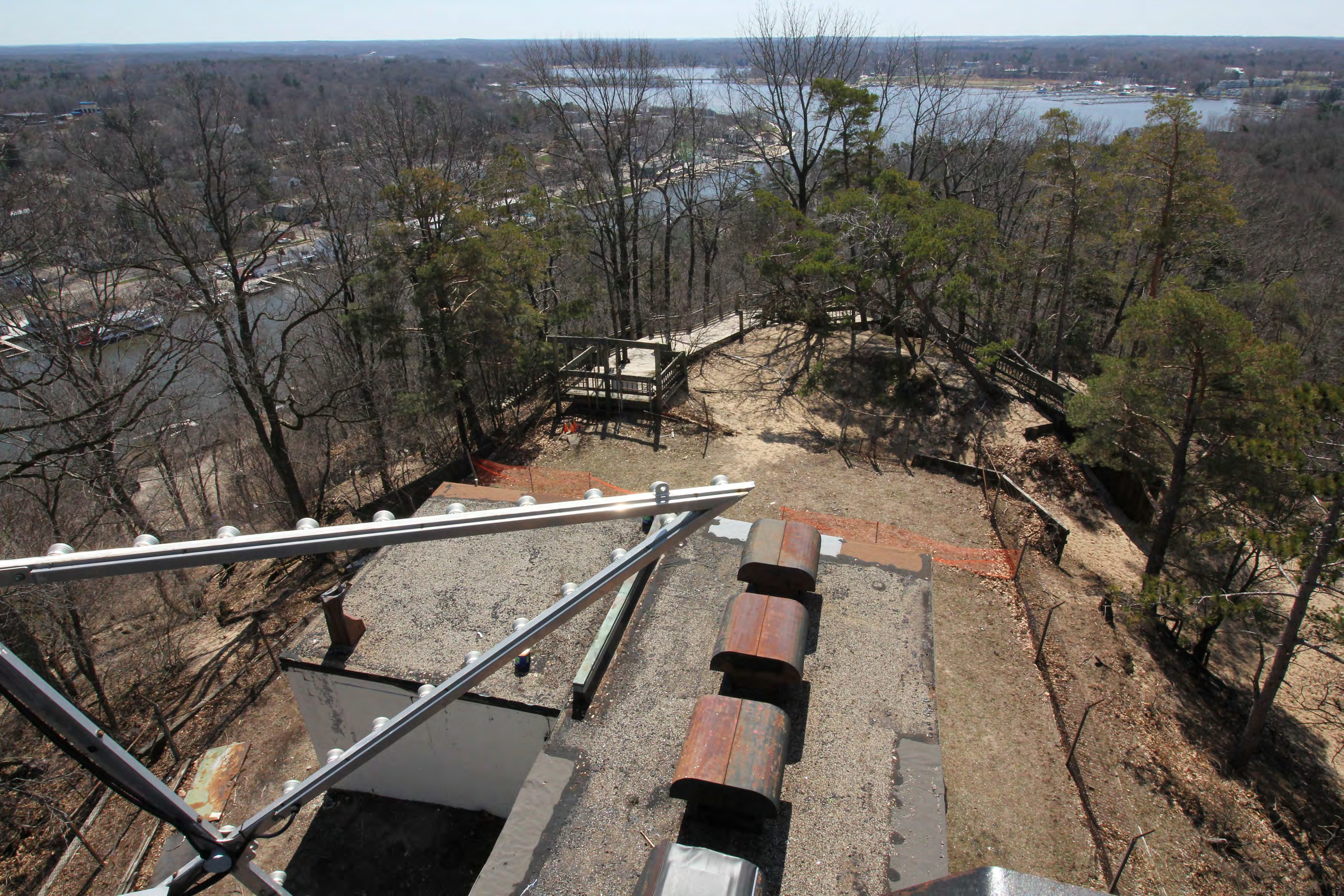 View from antenna tower, third landing, looking slightly east of south; star, equipment and generator building roof, southwest wooden retaining wall with Mt Baldhead Park Trail to Oval Beach just beyond descending to right, Mt Baldhead Park observation deck, and stairs descending left