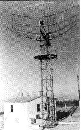 Historic Air Force photograph of the open-mesh AN/FPS-8 antenna on a lattice tower beside an equipment building